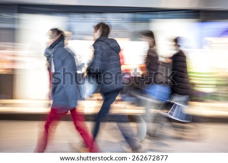Shopper walking against shop window at dusk, zoom effect, motion blur