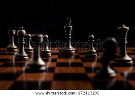 Bronze Chess Set on Black Background with Wooden Chess Board, Focusing on King