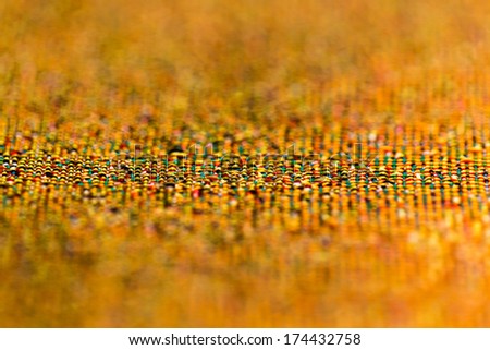 Bright abstract fabric texture with a predominance of orange and a small depth of field macro