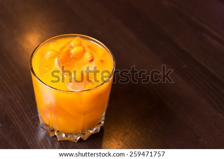 closeup cocktail orange and yellow sea buckthorn with a piece of ice above