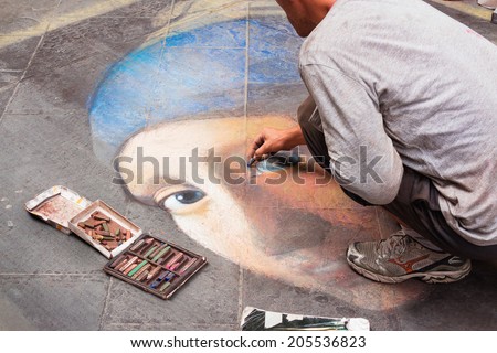 FLORENCE, ITALY A street artist draws the Girl with a Pearl Earring, the famous Vermeer painting, on asphalt on July 10, 2014 in Florence, Italy.
