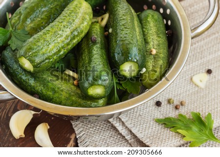Salted cucumbers. Cucumbers with low content of salt in the colander, on wooden background.
