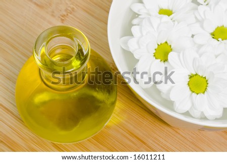 body oil and beautiful white daisies floating in a bowl of water