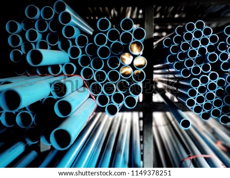 Multi size blue pvc pipe on the metal rack  with beam of sunlight
