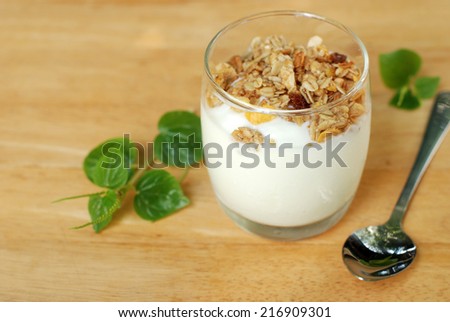 homemade yoghurt with muesli in a grass on wooden table.
