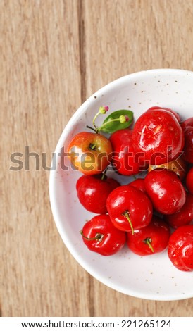 Small red fruit . Brazilian Acerola Fruit . small cherry in a bowl on wooden background.