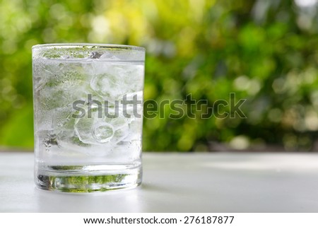 a glass of water with ice on nature background.