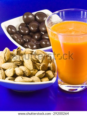 Juice of carrot and plate of almonds in center and defocused chocolate