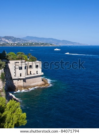 House on the sea and boats in Monaco with mountains in the background
