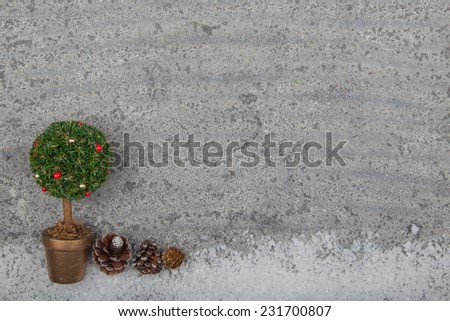 Decorated christmas tree ornament on grey stone background with fake snow