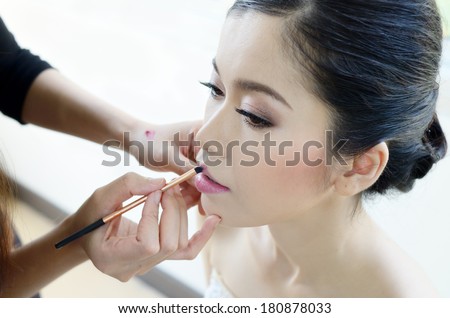 Asia woman applying lips makeup by makeup artist/Wedding makeup styles