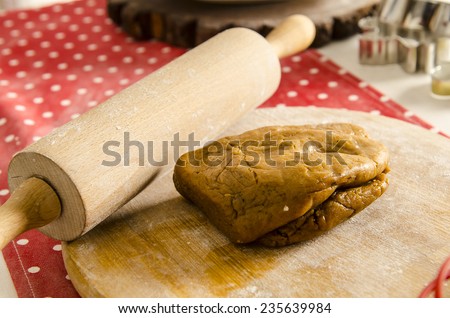 Beautiful kitchen with red tablecloth, rolling pin and dough for biscuit cake.