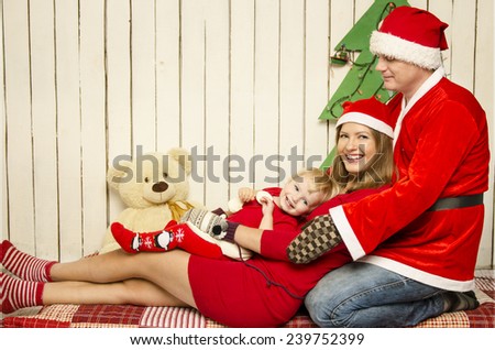 Happy family in Santa\'s cloth with snowman baby near Christmas tree and toys.  Father, mother and baby