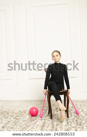 beautiful sport training rhythmic gymnastic girl with Rhythmic pink clubs doing professional exercises in white training room. sitting on wooden chair