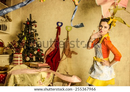 Beautiful and dressed up woman in kitchen with kitchen tools standing and smiling. America 60-s pin-up style.
