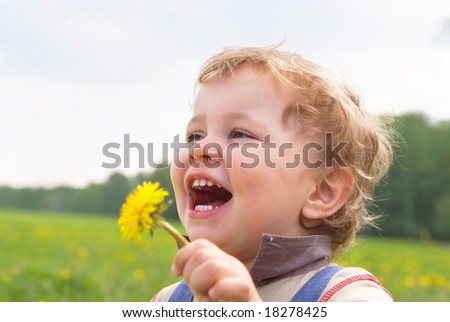 laughing little boy with dandelion in hand