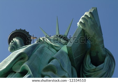 Looking upwards at the Statue of Liberty against clear blue sky