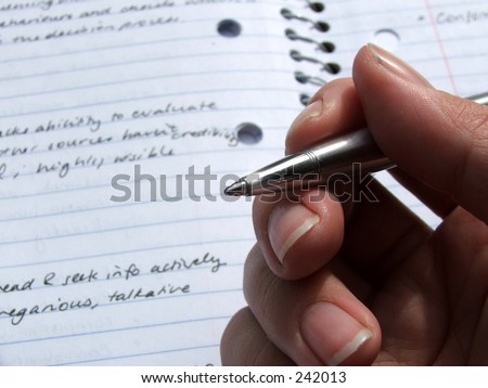 A hand holds a pen over a book