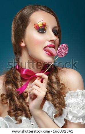 Young model with lollipop. Glossy lips. Fashion makeup. On a blue background. Concept of the sweet life.