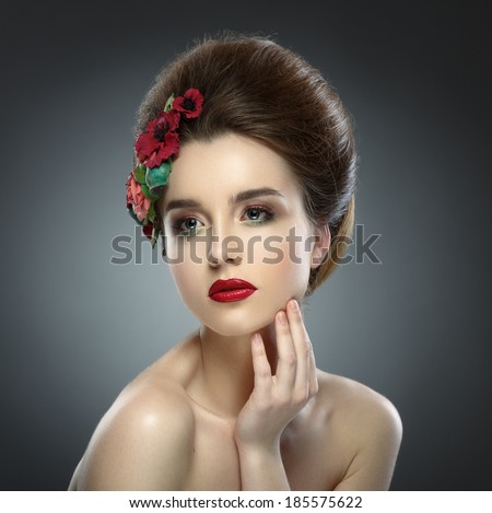 Beauty Portrait. Woman Touching her Face. Beautiful girl with colored make up and flowers in her hair.