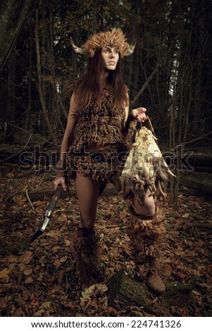 Ancient woman hunter in the forest with an ax in his hand. Historical costume.