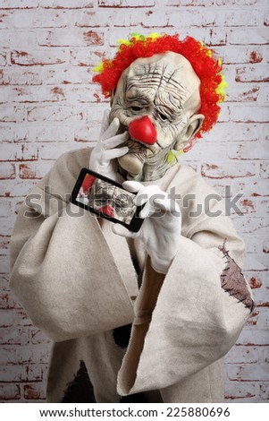Sad clown makes selfie on cellphone
