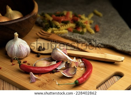 Spices assortment and pasta on a wooden table. Onions, garlic and chili. Shallow depth of field.