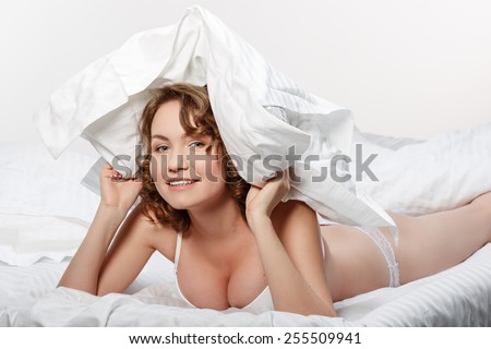 Girl in bed with a pillow over his head. Laughing girl in her bedroom.