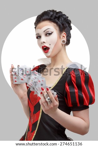 Portrait of a girl with fantasy make-up shuffles the playing cards