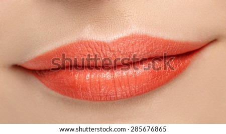 Beauty orange lip makeup detail. Sexy smiling lips. Beautiful makeup close up. Macro photography of sensual lips.