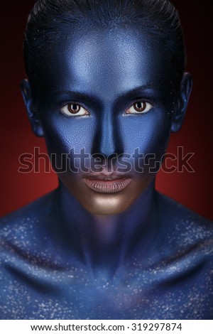 Beauty fashion Girl with colorful make-up, blue Paint on Skin. Halloween Alien Makeup. Creative visage.