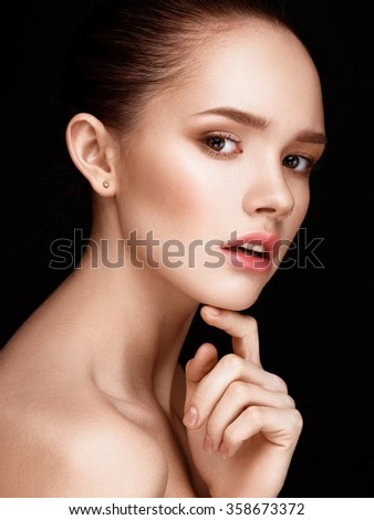 Close-up portrait of beautiful girl with clear healthy skin. Looking at the camera. Touching her face. Beauty studio shot.