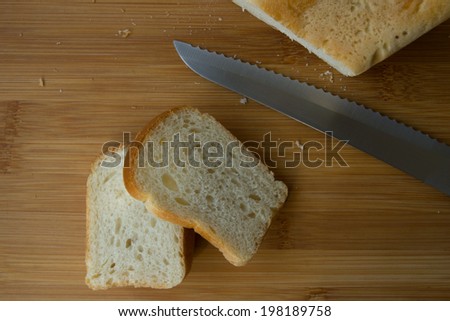 White bread on bamboo cutting board with bread knife