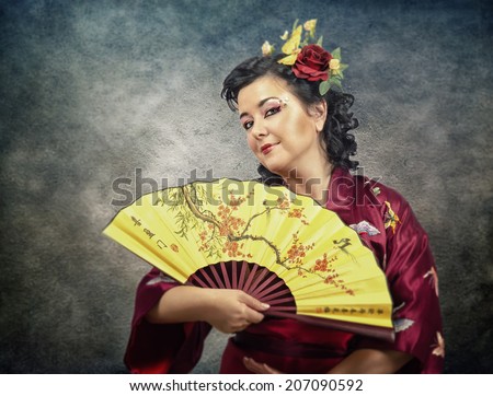 Half-length portrait of kimono mature caucasian woman with paper fan on grunge background