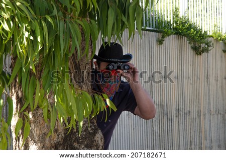 Cowboy in bandana looking through binoculars in ambush