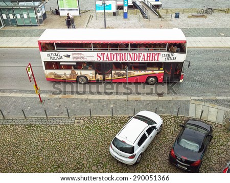Dresden, Germany-September 30, 2014: Top view on city tour bus moving in city waterfront.  Trip offers route with 22 different stops in Dresden. This picture was taken from Bruhl Terasse.