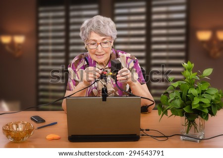 Old woman is trying to install audio video adapter by herself looking video manual in internet