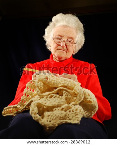 portrait of elderly woman is in red with  hook knitting (wool)