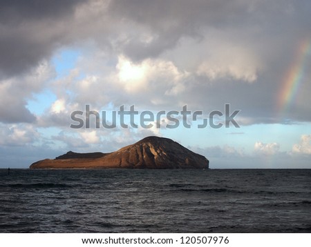 Rainbow goes into the water next to rabbit island in Waimanalo Bay on the windward side of Oahu, Hawaii.
