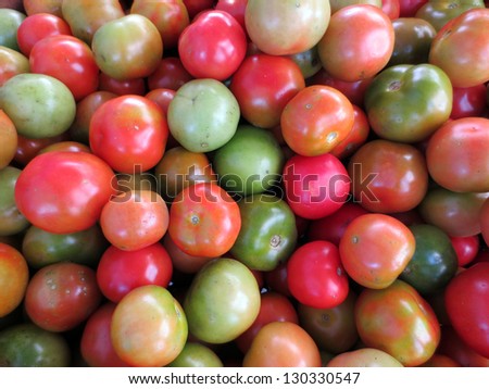 Tomatoes of Red, orange, and green color for sale at farmers market.
