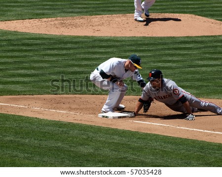 OAKLAND, CA - MAY 23: San Francisco Giants Vs. Oakland Athletics: Andres Torres slides back to 1st to beat a throw from the pitcher as 1st baseman Daric Barton tags.  May 23 2010 at the Coliseum Oakland California.