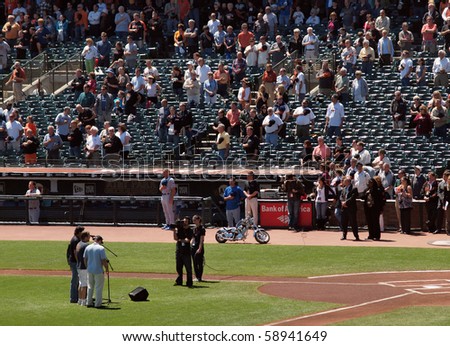 SAN FRANCISCO - AUGUST 12: Cubs vs Giants: Men sing national anthem in front of a camera on the field as players and fans stand with hats removed during national anthem.  August 12 2010 ATT Park.