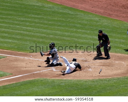 OAKLAND, CA - AUGUST 18: Blue Jays vs. Athletics: Cliff Pennington slides head first into home as Blue Jays catcher waits for incoming ball.  August 18 2010 at Coliseum in Oakland California.