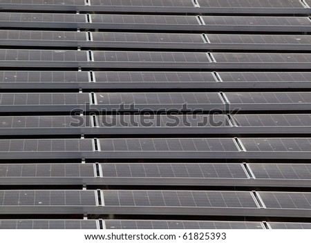 Flat-Roof top solar panel stretching into the distance on top of a baseball ballparks office.  Little bits of bird dropings can be seen on panels.