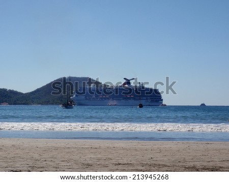 ZIHUATANEJO, MEXICO - JANUARY 10: Carnival Cruise ship rests in bay with small boats in forground seen from beach in Zihuatanejo, Mexico on January 10, 2010. Vessel is operated by Costa cruise line.