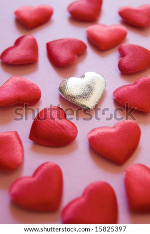 stock photo Silver heart amongst red hearts on pink background