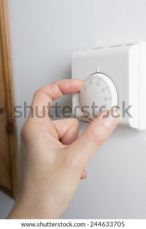 Close Up Of Female Hand On Central Heating Thermostat