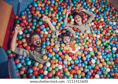 Top view. Happy family lying in pool with balls. Family rest, leisure concept. Spending holiday together. Entertainment center, mall, amusement park.