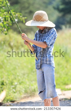 Portrait of teenage fisherman with stick at straw hat