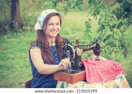 Happy woman with a vintage hand sewing machine